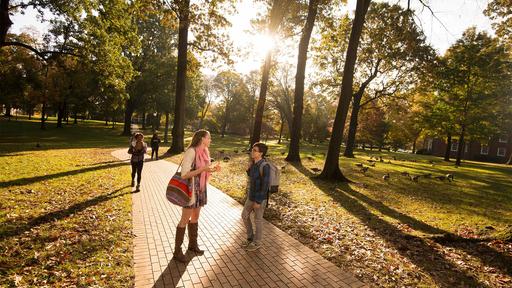 Two students chat on the Quad in the early morning sunshine.