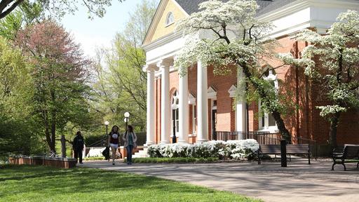 Students walk by the library as the spring flowers bloom.