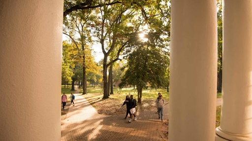 Students walk by the front of King Hall on a sunny day.