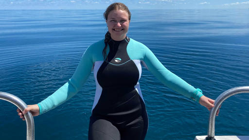 Photo of Gracie Perry-Garnette wearing a wetsuit and standing on a boat.