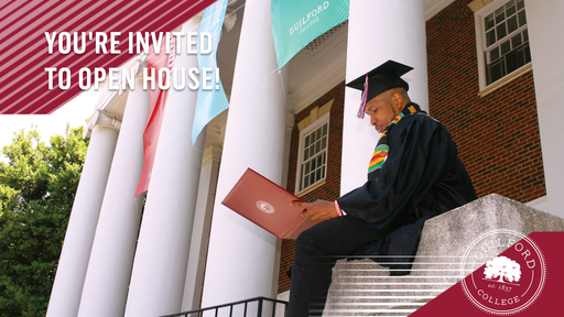 A student wearing a black graduation cap and gown looks at his diploma while sitting on the steps of Dana Auditorium.