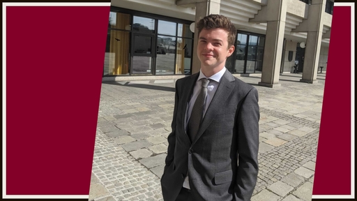 Jameson Lynch '20 stands in front of an office building wearing a gray suit, white shirt, and gray tie.