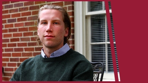 Ben James sits outside on Guilford's campus, wearing a green sweater over a blue shirt.