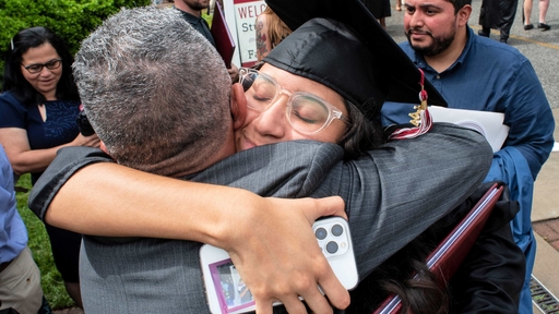 A student and a family member share a big hug outdoors after Commencement.