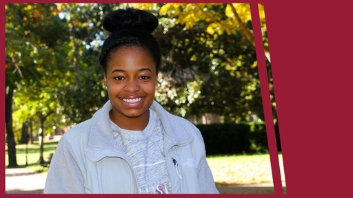 Cydney Scott stands outdoors on the Quad, wearing a gray shirt and gray jacket.