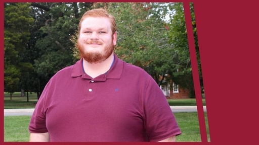 Jacob Perkins stands outdoors on Guilford's campus, wearing a red polo shirt.