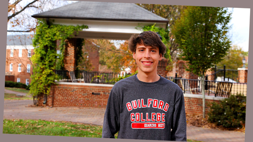 Noah West stands outdoors on Guilford's Quad, wearing a gray sweatshirt that says Guilford College, Quakers 1837.