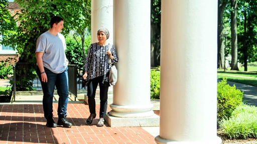 A student and a faculty member walk in front of Hege Academic Commons while talking.