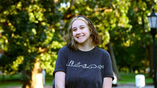 Emily Heck stands outside of New Garden Hall wearing a black tshirt.