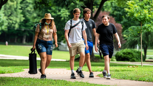 Four students walks across the Quad and chat.