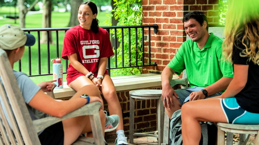Four students sit on Founders Patio, chatting over the summer break.