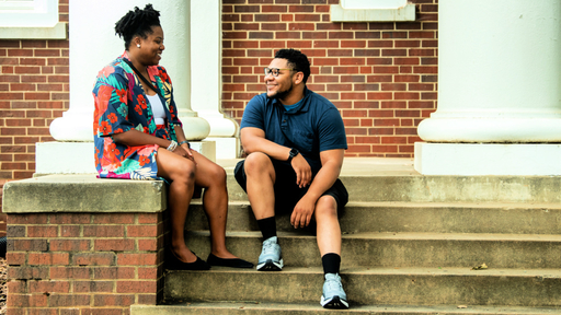 Two students sit and chat on the steps of King Hall.