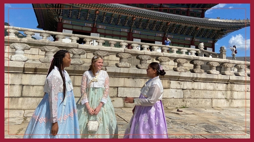 Sondria Lacewell (left) wearing a traditional blue dress, stands with two people in Korea, one wearing a green dress and one wearing a purple dress.