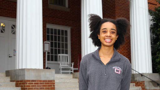 Tinyah Ervin '23 in front of New Garden Hall wearing a grey fleece shirt