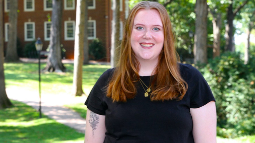 Taylor Calloway stands outdoors on Guilford's Quad, wearing a black t-shirt.