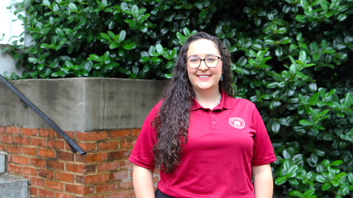 Kierston Walker wearing a burgundy polo, standing in front of New Garden Hall