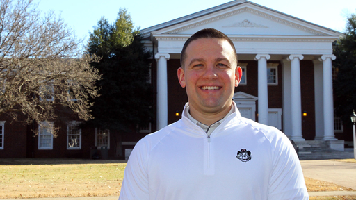 Bryan Mathews in front of Dana Auditorium in a white pullover shirt