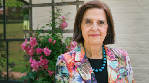Professional woman in colorful blazer and turquoise necklace on Guilford College campus.