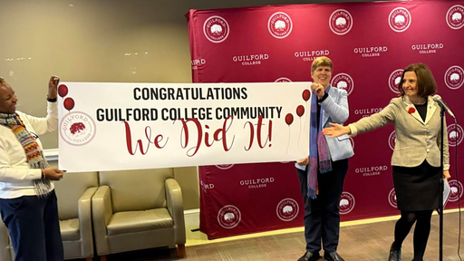 President Jean Bordewich, Provost Kami Rowan and Chief of Staff Meredeth Summers unfurl a banner which reads "we did it"
