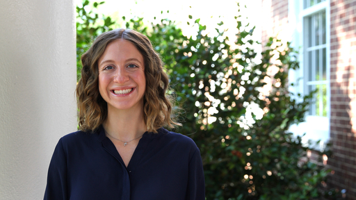 Lydia Saunders poses in front of King Hall wearing a dark blue blouse
