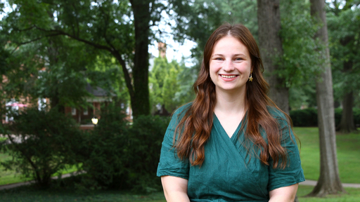 Trinity posing in the academic quad wearing a green dress