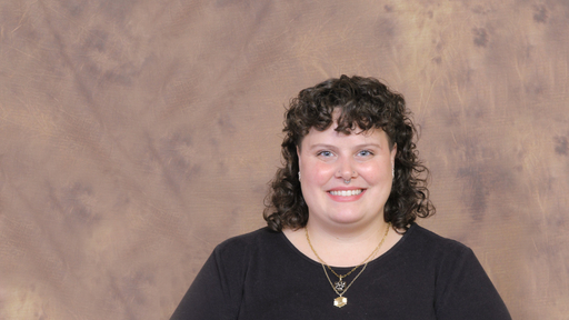 Shyla Butler poses in a black shirt in front of a brown backdrop