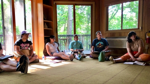 Guilford College students sitting in a circle on the floor during a cabin discussion.