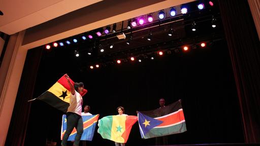 Students wave flags in a parade at African Night.