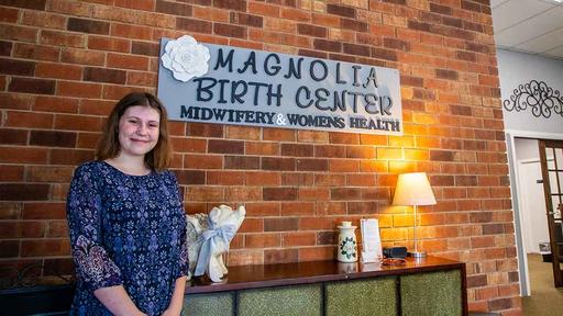 Hannah Kaplan stands next to the sign at Magnolia Birth Center.