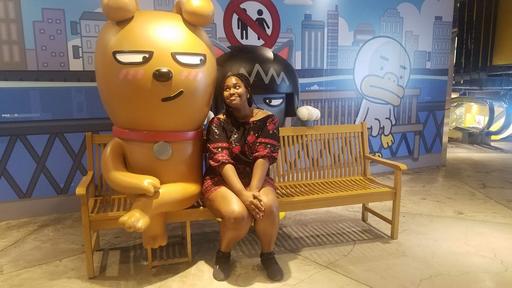 Student Mikayla Jones poses for a portrait with a large golden bear in Seoul, South Korea.