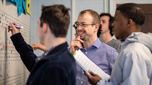 Music Professor Drew Hayes teaches a music theory class at the whiteboard.